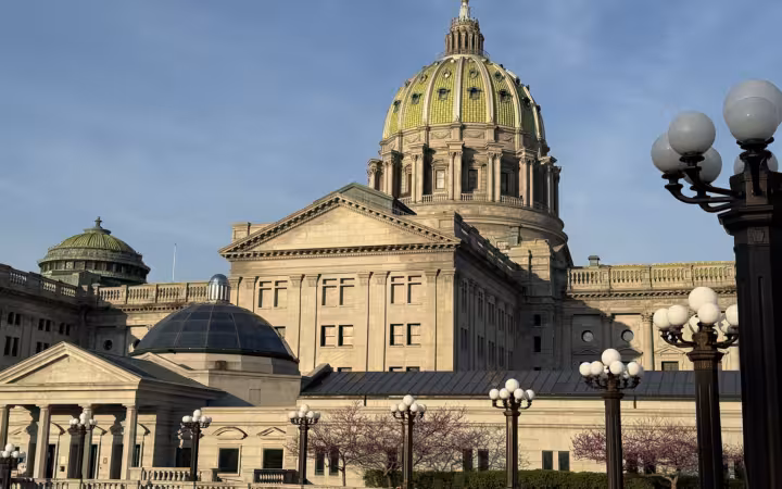 Pennsylvania State Capitol dome rises above its east wing and ornate lamps