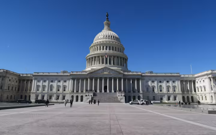 The United States Capitol East Front beneath clear skies, with pedestrians on the plaza