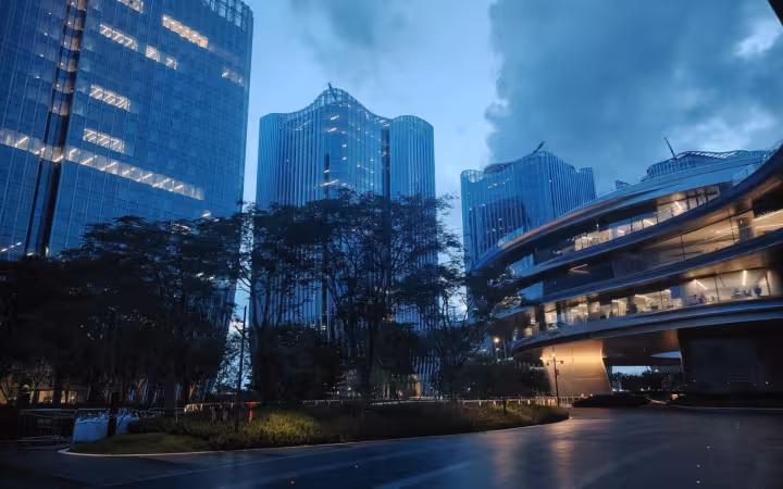Tencent headquarters campus buildings rise behind trees at dusk in Shenzhen