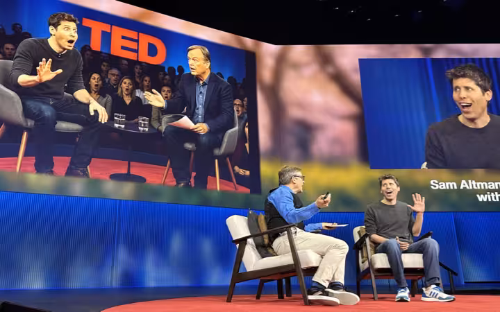 Sam Altman speaking on a TED stage beside an interviewer and projected portraits