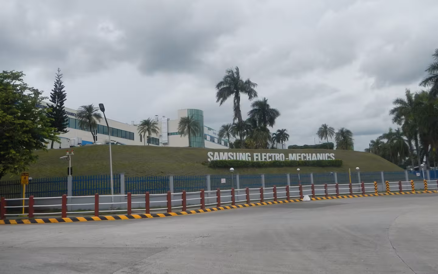 Samsung Electro-Mechanics facility and sign behind a fence and empty road