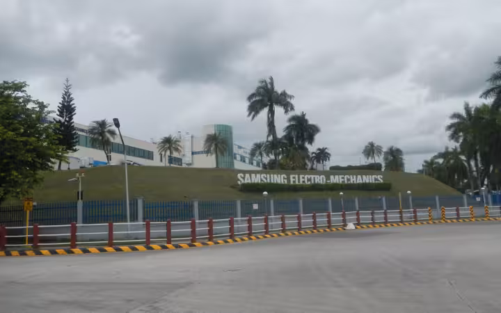 Samsung Electro-Mechanics facility and sign behind a fence and empty road