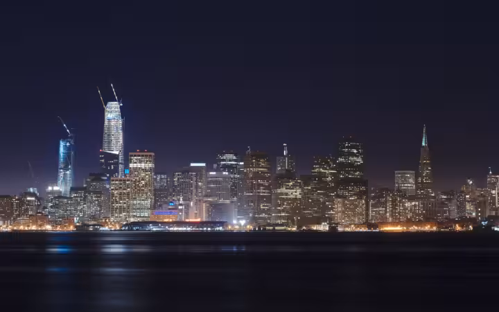 San Francisco skyline illuminated at night across water from Treasure Island