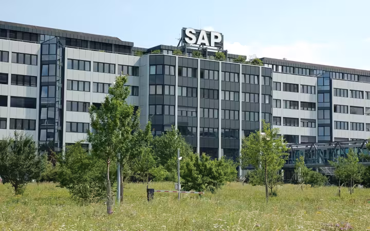 SAP headquarters building in Walldorf behind trees and a grassy foreground