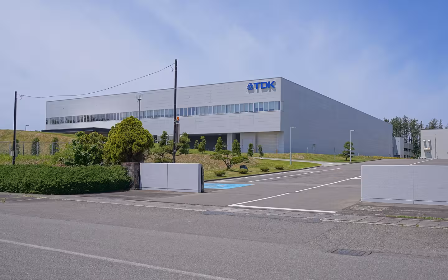 TDK Inakura Factory west site behind an empty road and landscaped grounds