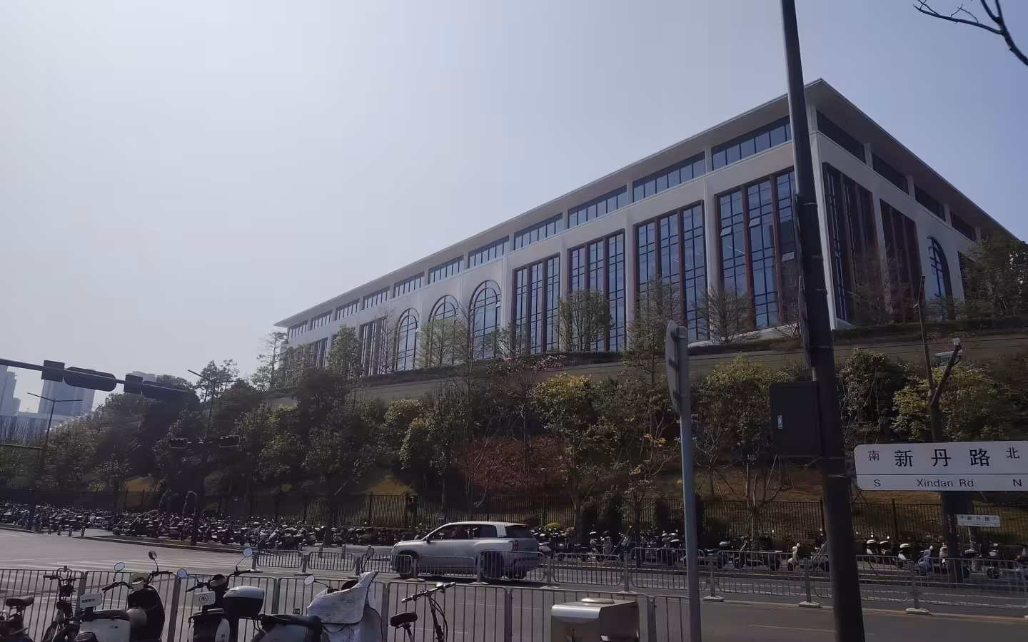 Huawei Guanlan campus building above a road lined with parked scooters.