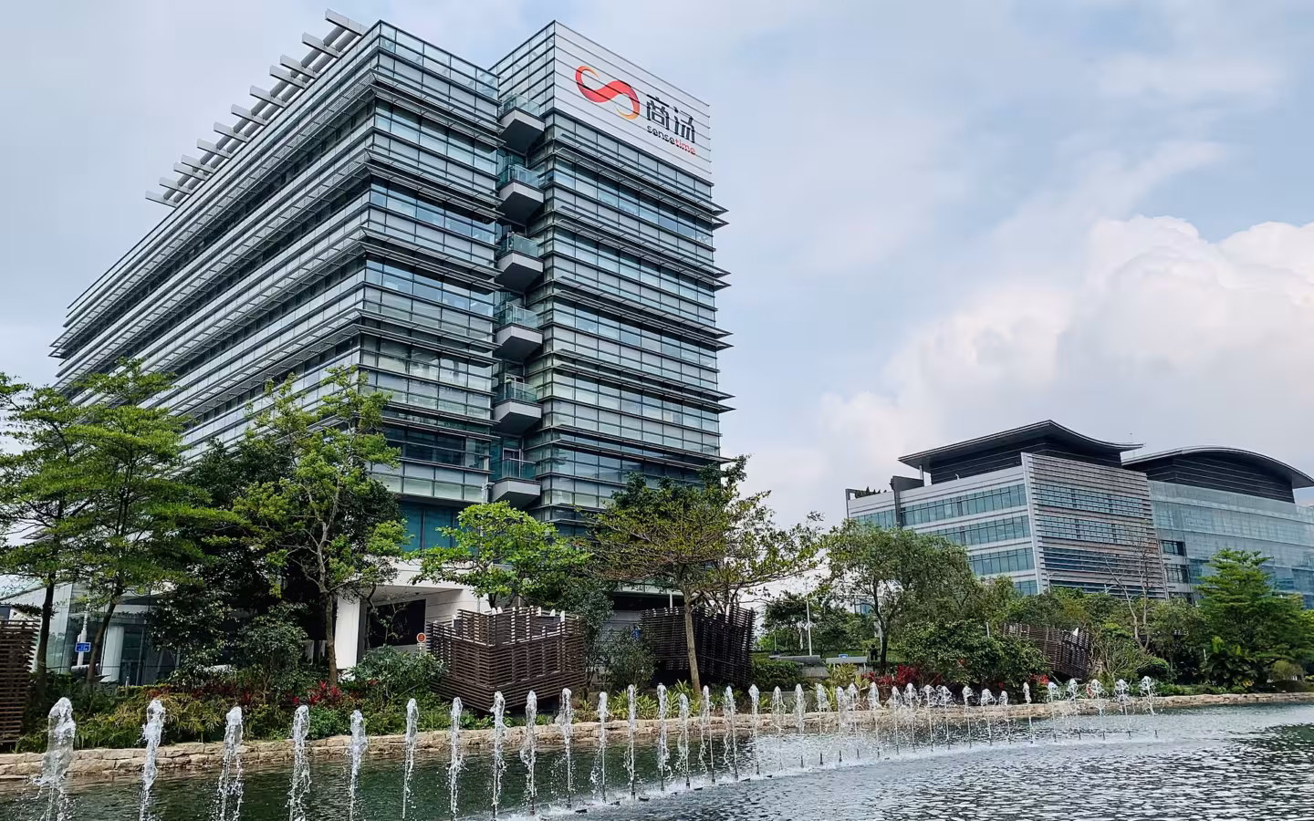 SenseTime's Hong Kong HQ rises behind trees and a fountain.