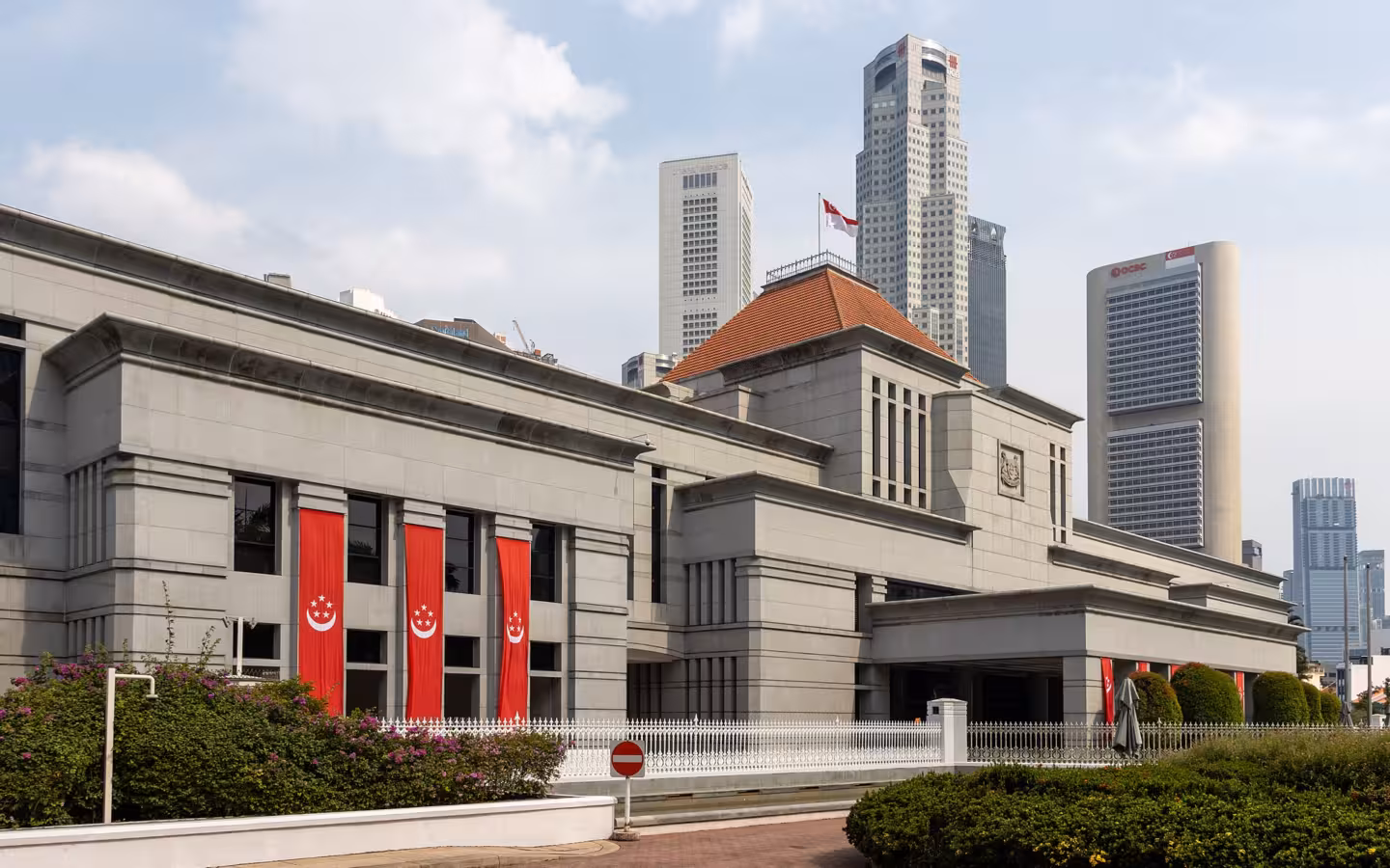 Parliament House, Singapore, with red banners and skyscrapers behind it