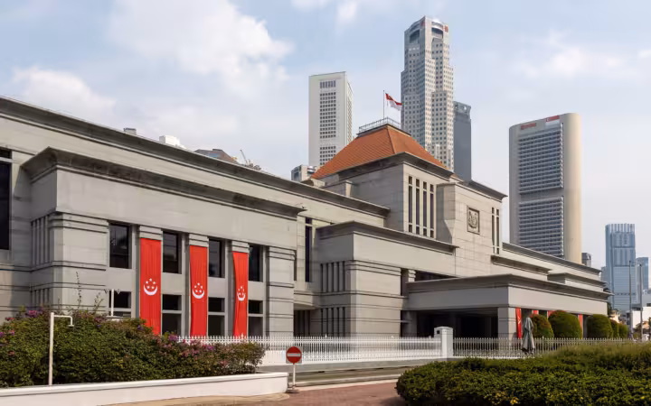 Parliament House, Singapore, with red banners and skyscrapers behind it