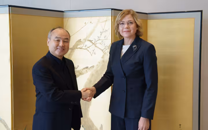 Henna Virkkunen is shaking hands with Masayoshi Son before a gold screen