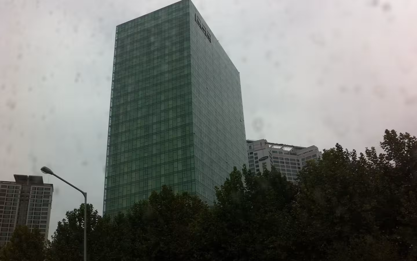 The NHN headquarters rises above trees beneath a cloudy, speckled sky