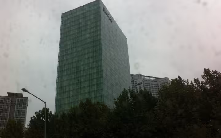 The NHN headquarters rises above trees beneath a cloudy, speckled sky