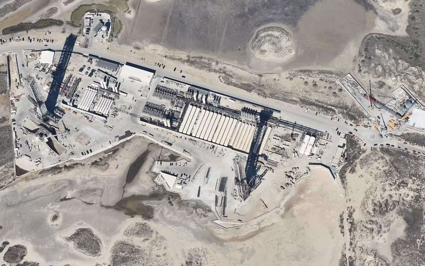 An aerial view of SpaceX Starbase launch facilities amid coastal terrain.