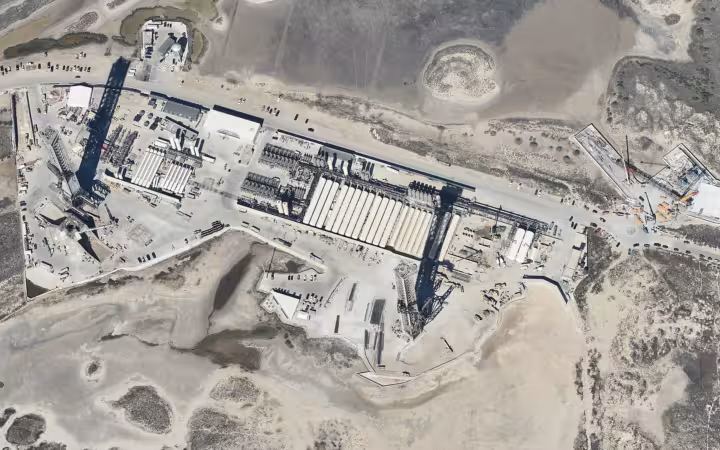An aerial view of SpaceX Starbase launch facilities amid coastal terrain.