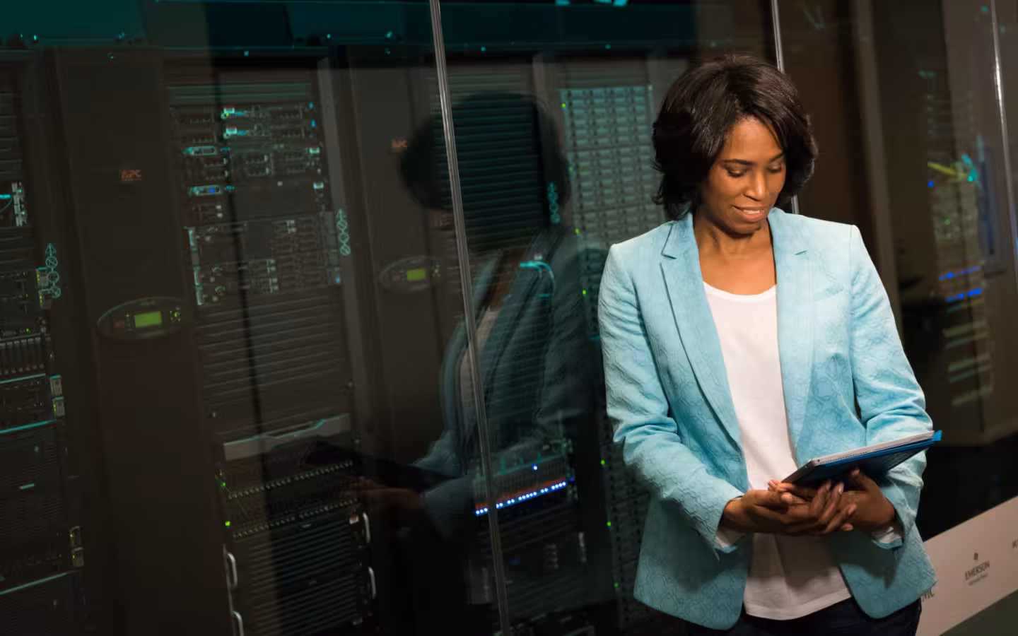 IT professional holding a tablet beside server racks in a data center