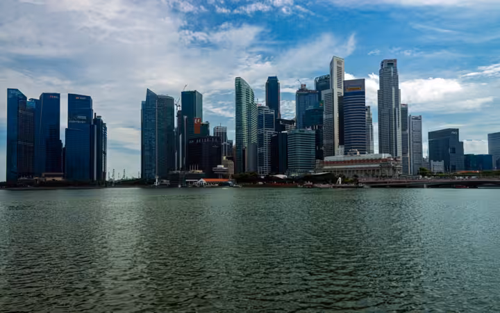 Singapore Financial District skyline stretches across Marina Bay beneath cloudy skies.