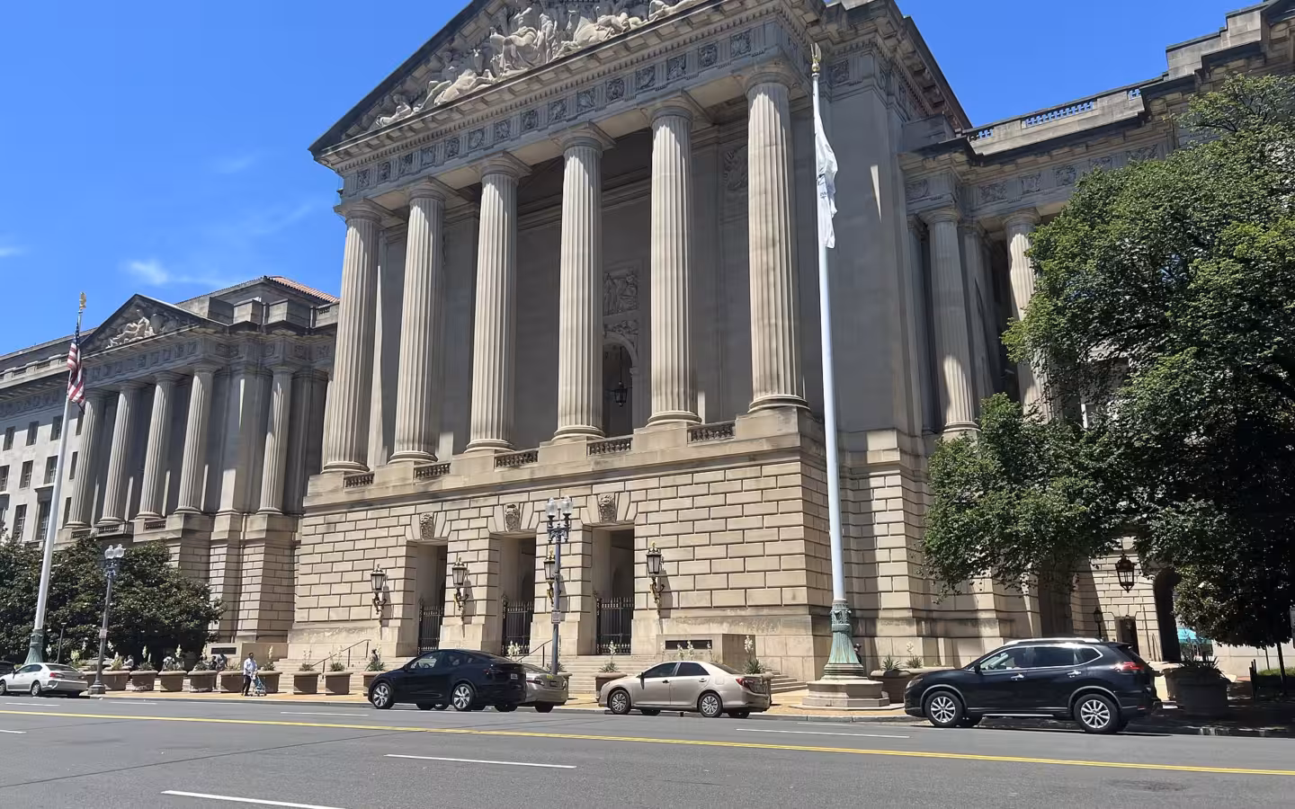 The columned facade of Andrew W. Mellon Auditorium beside a street with cars