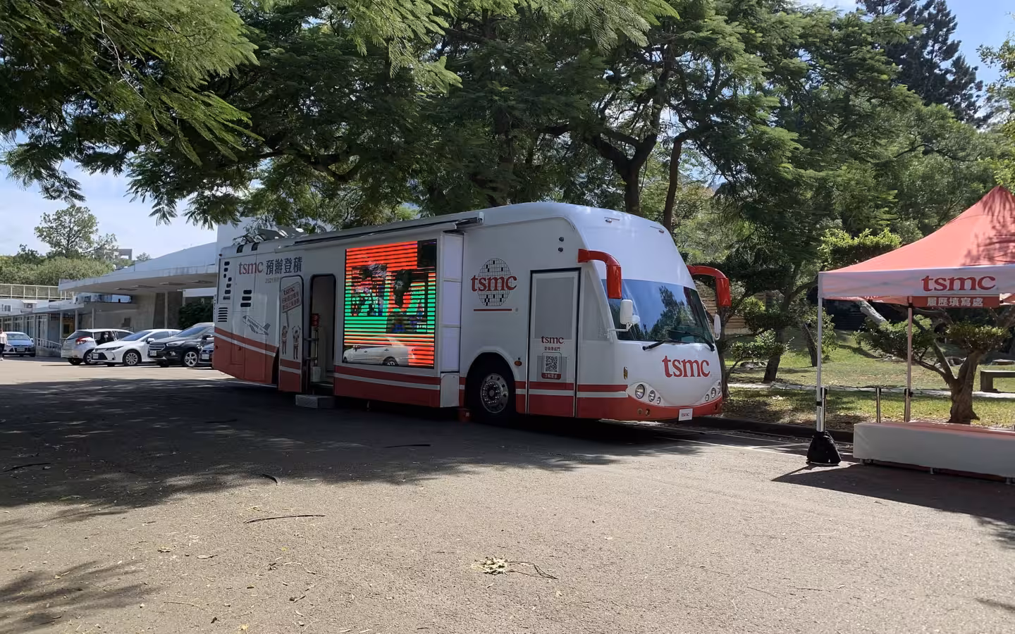 A TSMC mobile recruiting office bus parked beside a branded canopy