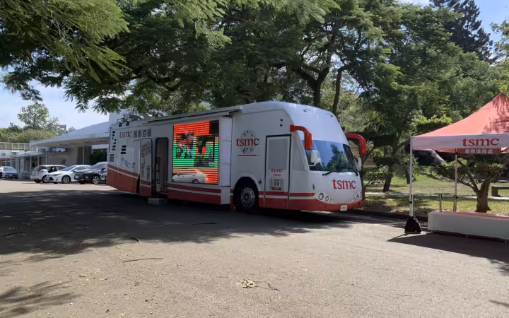 A TSMC mobile recruiting office bus parked beside a branded canopy