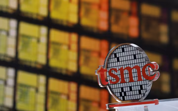 A TSMC logo at its Hsinchu headquarters, with colorful windows behind it