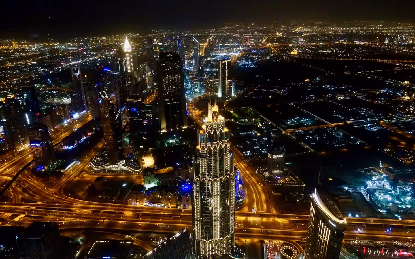 Illuminated Dubai skyscrapers and highways seen from above at night