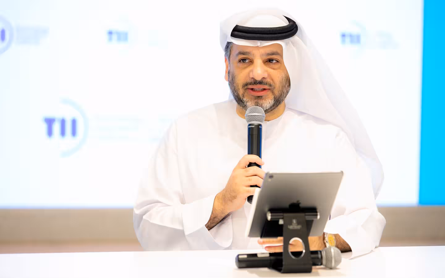 Faisal Al Bannai speaks into a microphone behind a tablet.