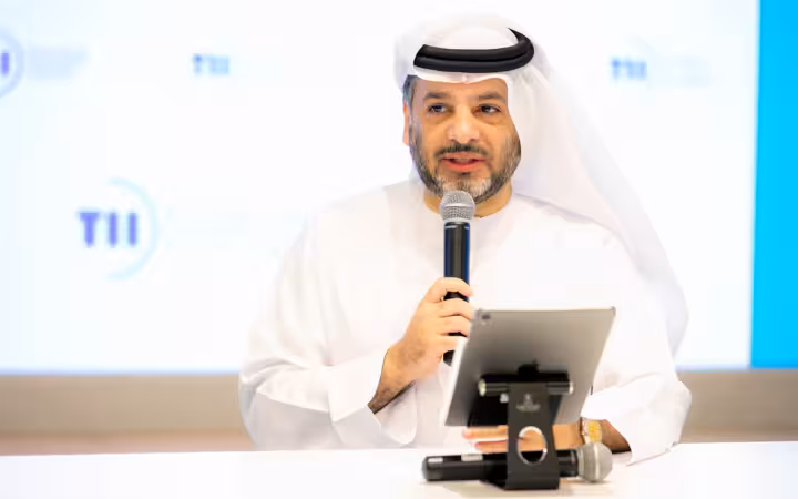 Faisal Al Bannai speaks into a microphone behind a tablet.