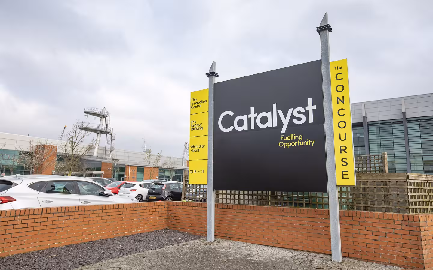 Catalyst sign outside a Belfast building, with parked cars and an overcast sky