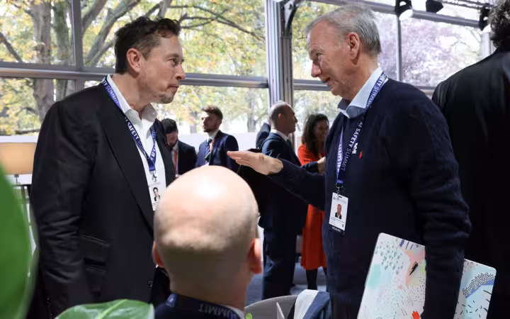 Elon Musk and Eric Schmidt talking among attendees at Bletchley Park