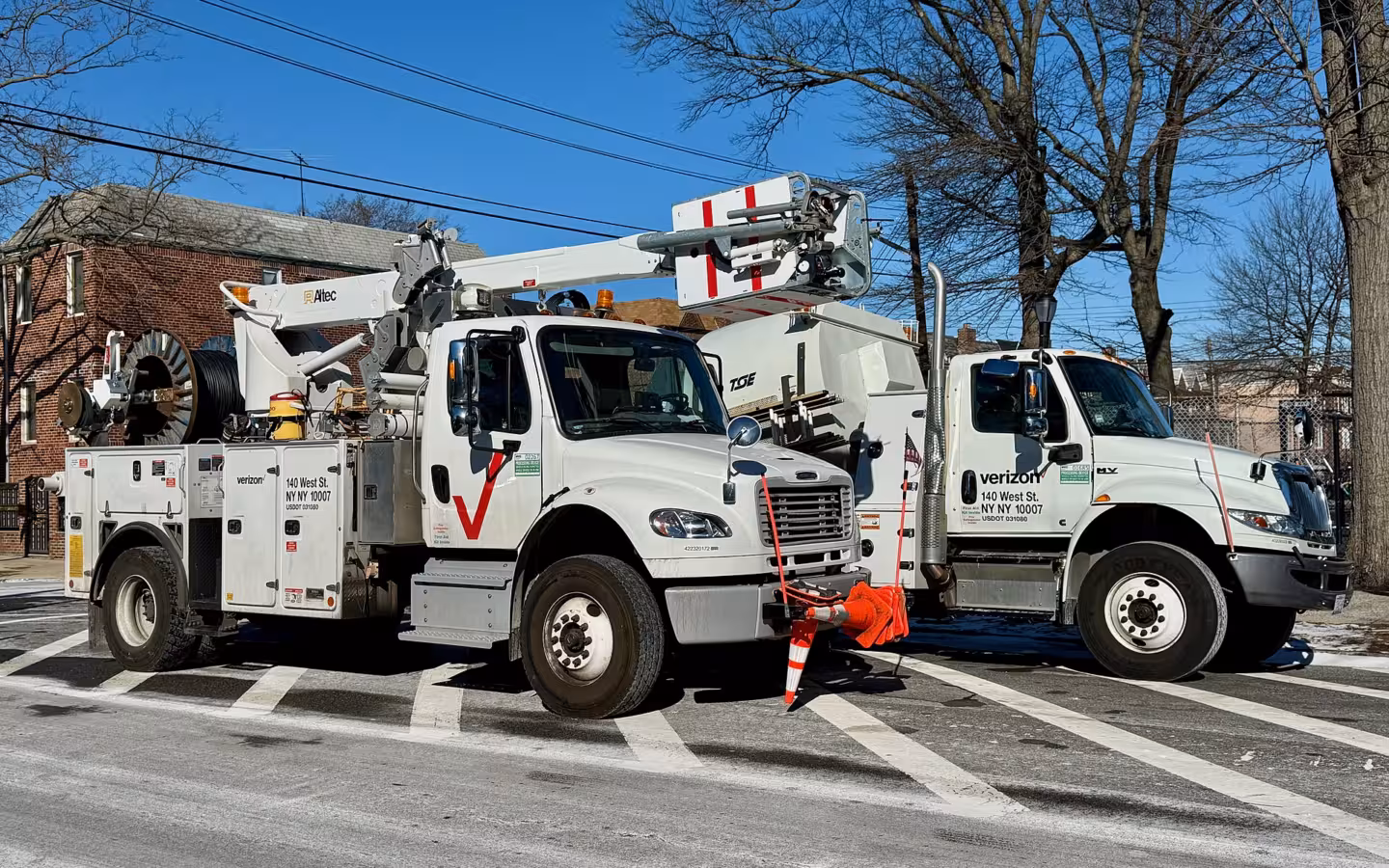 Two Verizon-branded Altec bucket trucks parked side by side outdoors.