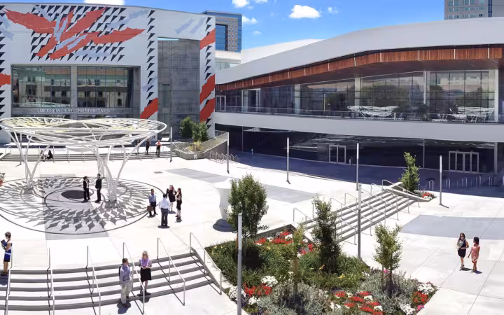 San Jose McEnery Convention Center and its sunlit plaza with scattered pedestrians