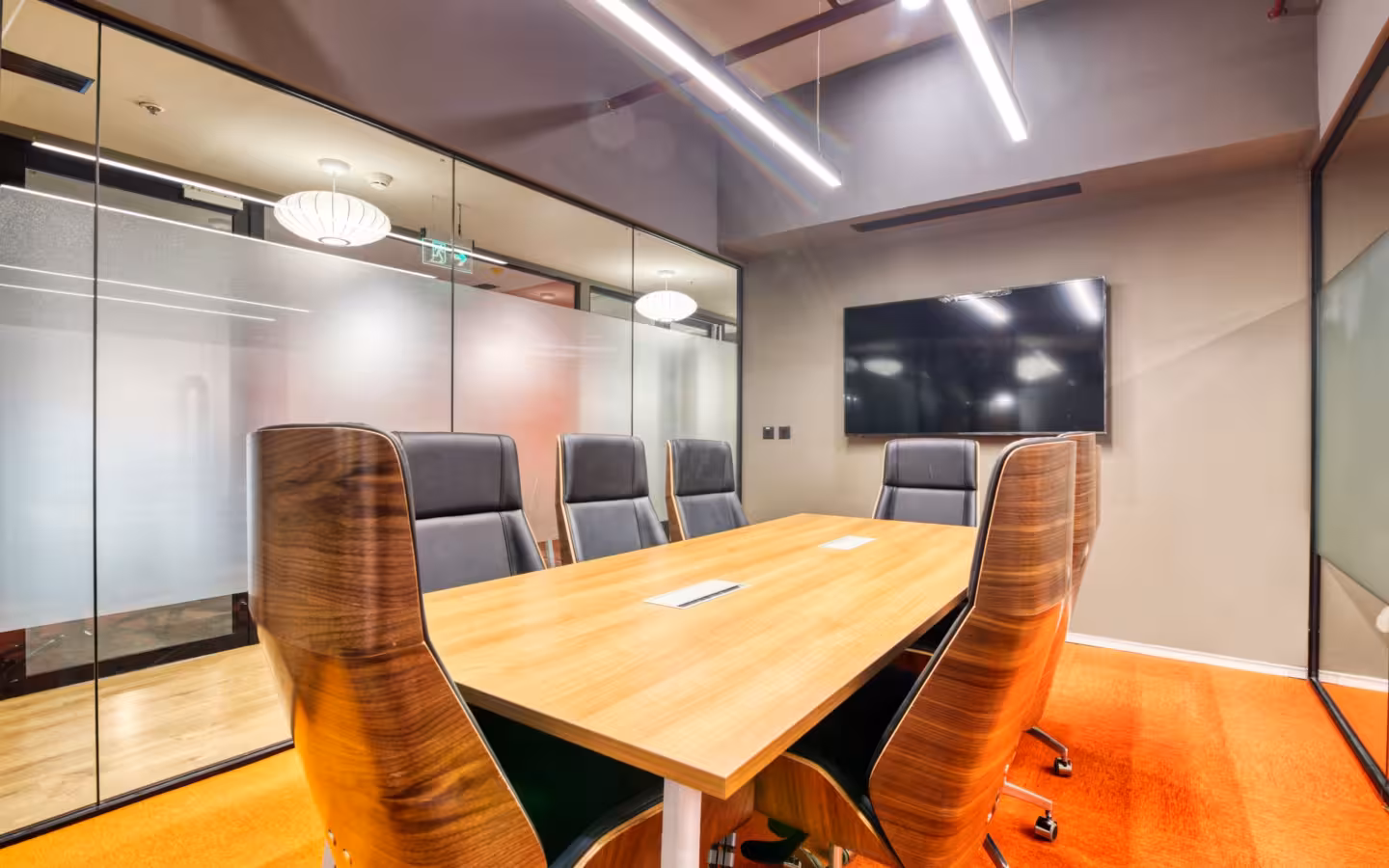 Conference room with sleek wooden table, modern chairs, glass walls
