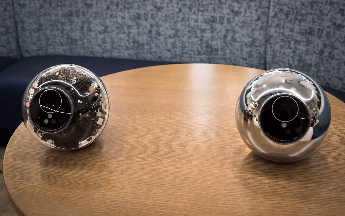 Two Worldcoin orbs sit apart on a wooden table.