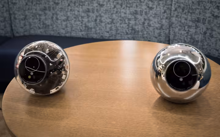 Two Worldcoin orbs sit apart on a wooden table.