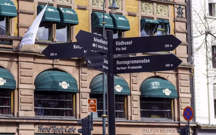 Directional signs in central Oslo stand outside a Hard Rock Cafe.